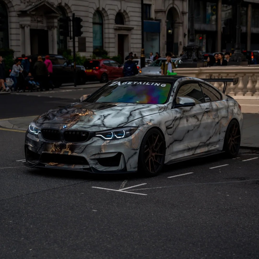 A BMW M4 coupe with a custom white and gray marble wrap.