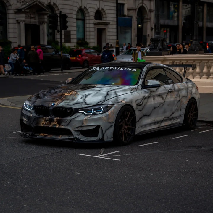 A BMW M4 coupe with a custom white and gray marble wrap.